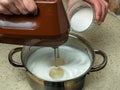 The cook whips raw egg whites with an electric mixer in an iron pan. Close-up of a womans hands making meringues Royalty Free Stock Photo