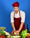 Cook works in kitchen near table with vegetables and tools. Royalty Free Stock Photo