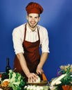 Cook works in kitchen near table with vegetables and tools. Royalty Free Stock Photo