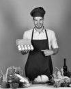 Cook works in kitchen near table with vegetables and tools. Dairy cuisine and cooking concept. Chef with happy face Royalty Free Stock Photo