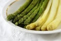 cooked asparagus, green and white on a plate, white table cloth, closeup