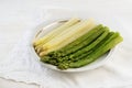 Cooked asparagus, green and white on a plate, white table with n