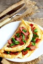 Cooked bacon omelet. Homemade spicy omelet with fried sliced bacon and parsley on a white plate, fork, knife on old wooden table Royalty Free Stock Photo