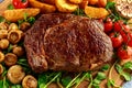 Cooked Beef Ribeye Steak with Potato, Mushrooms, tomatoes on wooden board. Royalty Free Stock Photo