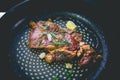 Cooked beef steak with rosemary and garlic inside iron skillet