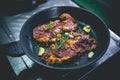 Cooked beef steak with rosemary and garlic inside iron skillet