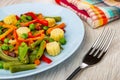 Cooked vegetable mix in plate, napkin, fork on wooden table Royalty Free Stock Photo