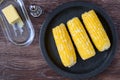 Cooked corn on the cob on a black plate, salt shaker, butter dish Royalty Free Stock Photo