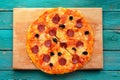 Cooked cut salami pizza on turquoise background Royalty Free Stock Photo