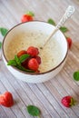 cooked diet oatmeal in a bowl with fresh ripe strawberries