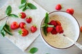 cooked diet oatmeal in a bowl with fresh ripe strawberries