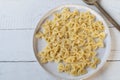 Cooked farfalle or bow tie pasta on a plate on white background