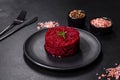 Cooked grated beetroot formed as a cylinder and ready dish on a black plate