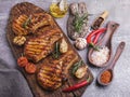 Cooked grilled meat pork, beef, chop on bone, on cutting board, spices, tomato, garlic, rosemary Royalty Free Stock Photo