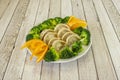 Cooked gyozas stuffed with pork accompanied by pieces of broccoli boiled al dente and orange slices