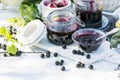 Cooked homemade black currant jam in small glass bowl and jars on white wooden table, fresh black currant jam close up Royalty Free Stock Photo