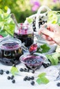 Cooked homemade black currant jam in small glass bowl and jars on white wooden table, fresh black currant jam close up Royalty Free Stock Photo