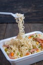 Cooked instant noodle with ingredients and plastic fork