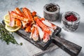 Cooked King Crab legs meat on a wooden board with herbs. White background. Top view