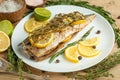 Cooked mackerel on a white plate with spices, herbs, lemon, lime and salt. A close-up, on a wooden background.Concept of homemade