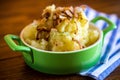 Cooked mashed potatoes with fried chopped bacon and onions.