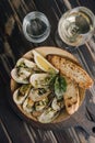 Cooked mussels in clay dish with bread and white wine glass Royalty Free Stock Photo