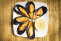 Cooked mussels with parsley and orange sauce and half a lemon on a white plate Royalty Free Stock Photo