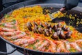 Cooked paella with shrimp, musse, rice in huge pan at street food festival