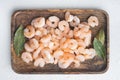 Cooked peeled prawns, shrimps, on wooden tray, on white stone background, top view flat lay