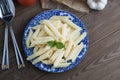 Cooked penne pasta with butter,cheese and fresh vegetable ingredients on background: tomato, garlic, onion, fork and