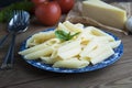 Cooked penne pasta with butter,cheese and fresh vegetable ingredients on background: tomato, garlic, onion, fork and spoon, basil.