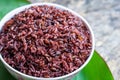 Cooked purple rice berry in bowl over green leaf background