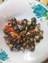 Cooked Rice Field Snail Meat with Hot Chillies on White Plate over Bamboo Surface Royalty Free Stock Photo