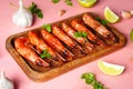 Cooked shrimp and langoustines, king prawns with lime, garlic and parsley. Grilled and fried on pink background Royalty Free Stock Photo