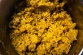 Cooked steamed orange quinoa grits in a pan close up