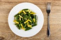 Cooked yellow and green beans in plate, fork on table. Top view