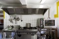 Cooker system from steel with stove, grill, oven and extractor hood in a professional canteen kitchen