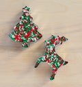 Christmas tree and reindeer shaped cookie cutters filled with candy sprinkles on a wood background Royalty Free Stock Photo