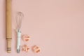 Cookie cutters, whisk, rolling pin and kitchen bake tools for making sweets. Pastel pink background. Top view of a holiday baking