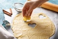 Cookie dough hearts in hand on blue background with rolling pin, strainer and cinnamon