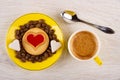 Cookie with jam heart, coffee beans, sugar in saucer, cup with espresso, spoon on table. Top view Royalty Free Stock Photo