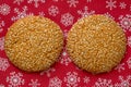 Cookie with sesame on red Christmas background with snowflakes Royalty Free Stock Photo