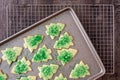 Cookie sheet filled with baked Christmas Tree cookies, cooling rack