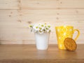 A cookie and a yellow cup of coffee and  a bunch of daisies in the background Royalty Free Stock Photo