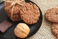 Cookies with chocolate and walnuts on a black plate. Food photo on a natural background made of burlap. Copy space. Clouse up. Top