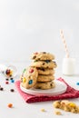 Cookies with colorful candies and chocolate chips and a bottle of milk on white background. Side view, copy space. Multicolor Royalty Free Stock Photo