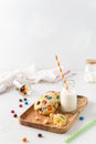 Cookies with colorful candies and chocolate chips and a bottle of milk on white background. Side view, copy space. Multicolor Royalty Free Stock Photo