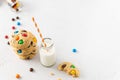 Cookies with colorful candies and chocolate chips and a bottle of milk on white background. Side view, copy space. Multicolor Royalty Free Stock Photo