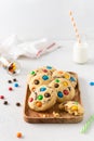 Cookies with colorful candies and chocolate chips and a bottle of milk on white background. Side view. Multicolor biscuits for Royalty Free Stock Photo