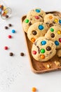 Cookies with colorful candies and chocolate chips on wooden tray on white background. Side view, close up. Multicolor biscuits for Royalty Free Stock Photo